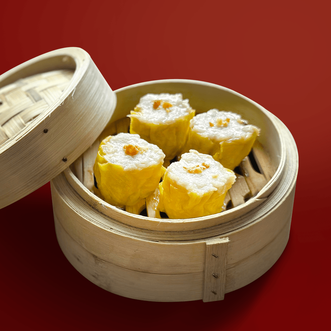Steamed siomai dumplings in a traditional bamboo steamer basket on a red background – Chinese dim sum cuisine